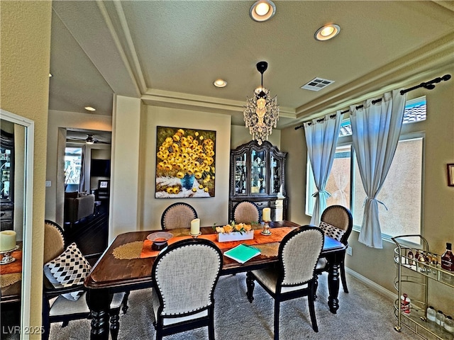 carpeted dining space featuring a raised ceiling and a healthy amount of sunlight