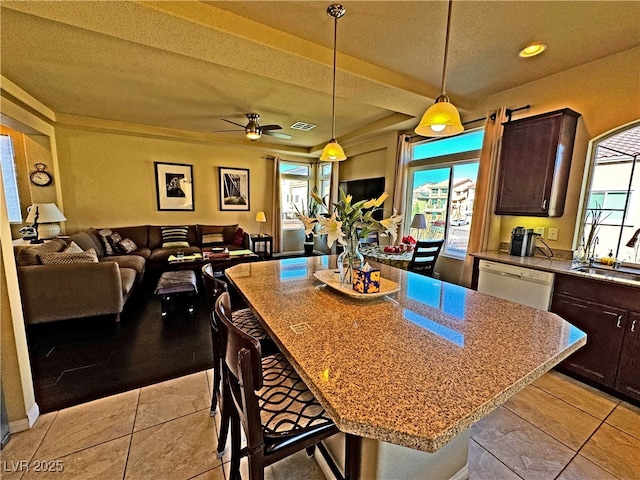 kitchen featuring dishwasher, hanging light fixtures, dark brown cabinets, a kitchen breakfast bar, and a kitchen island