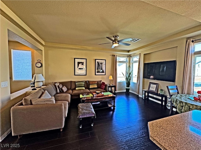 living room with ceiling fan, dark wood-type flooring, and a textured ceiling