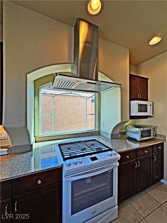 kitchen with stainless steel range with gas cooktop, light stone counters, dark brown cabinetry, and light tile patterned floors