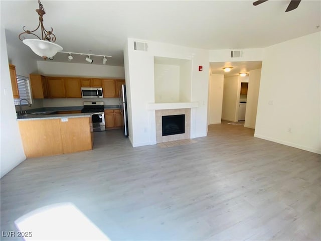 kitchen featuring hanging light fixtures, appliances with stainless steel finishes, light hardwood / wood-style floors, and kitchen peninsula