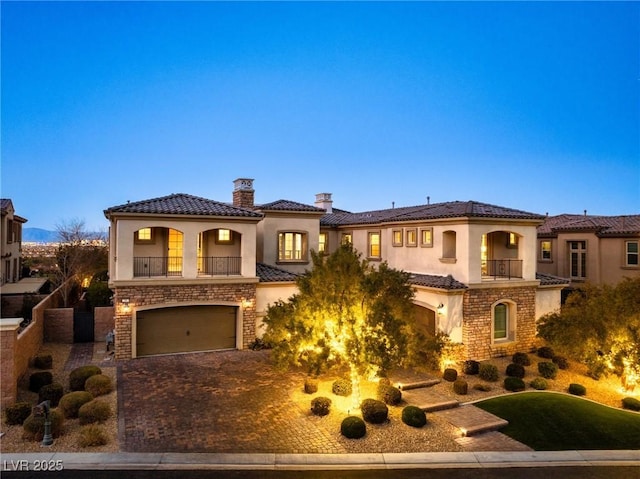 mediterranean / spanish-style house featuring a garage and a balcony