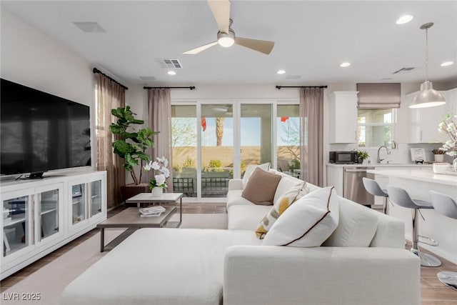 living room featuring sink, wood-type flooring, and ceiling fan