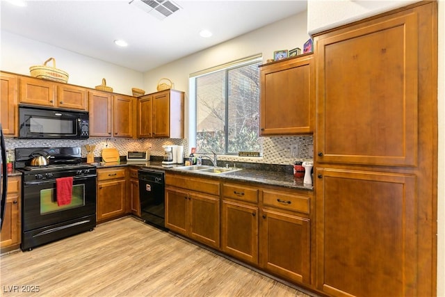 kitchen featuring sink, backsplash, light wood-type flooring, and black appliances