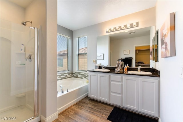 bathroom featuring hardwood / wood-style flooring, plus walk in shower, and vanity