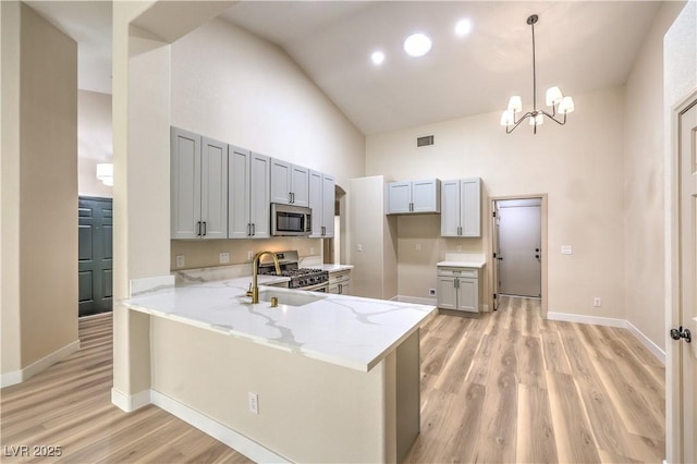 kitchen featuring high vaulted ceiling, decorative light fixtures, sink, kitchen peninsula, and stainless steel appliances