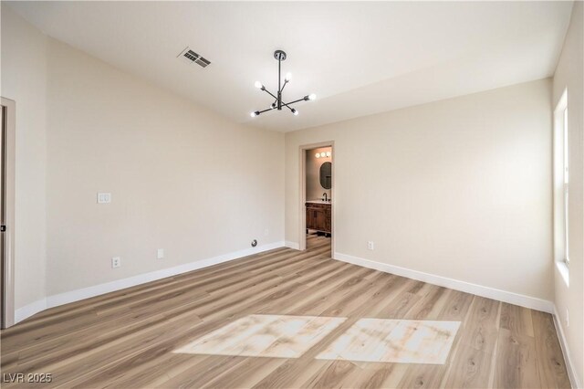 empty room with light wood-type flooring and an inviting chandelier