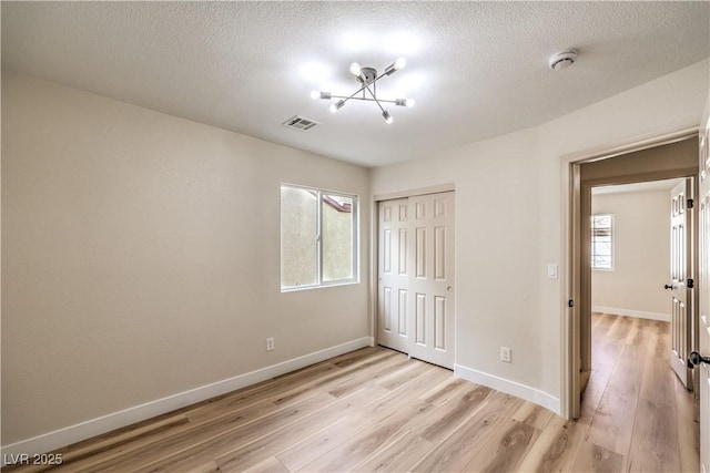 unfurnished bedroom with a textured ceiling, light wood-type flooring, and a closet