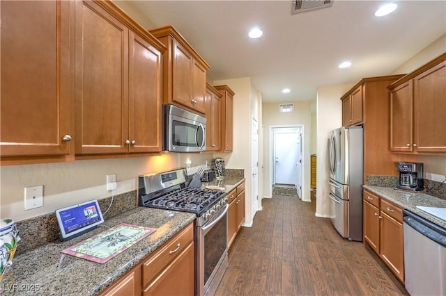 kitchen featuring dark hardwood / wood-style floors, dark stone counters, and appliances with stainless steel finishes