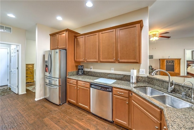 kitchen with appliances with stainless steel finishes, stone countertops, sink, dark hardwood / wood-style flooring, and ceiling fan