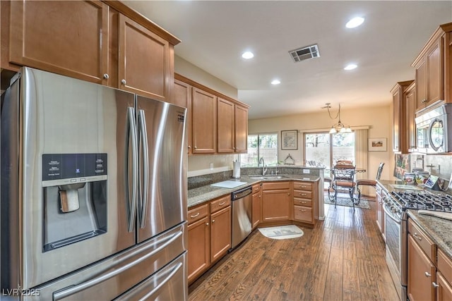 kitchen featuring pendant lighting, sink, appliances with stainless steel finishes, light stone countertops, and kitchen peninsula