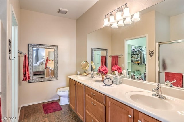 bathroom featuring vanity, hardwood / wood-style flooring, a shower with door, and toilet