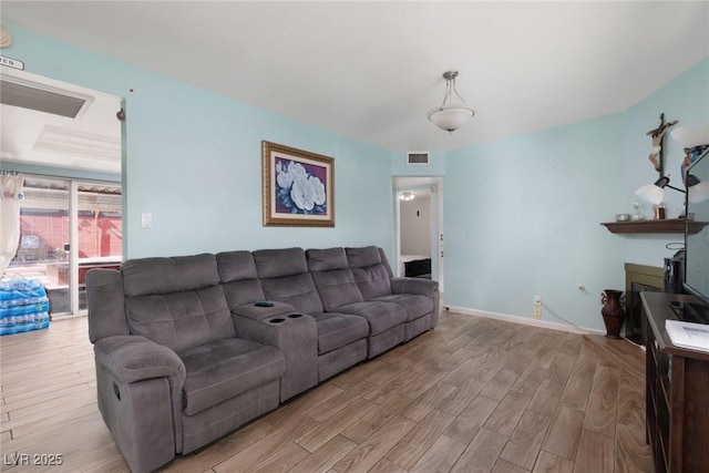 living area with light wood-type flooring, visible vents, and baseboards