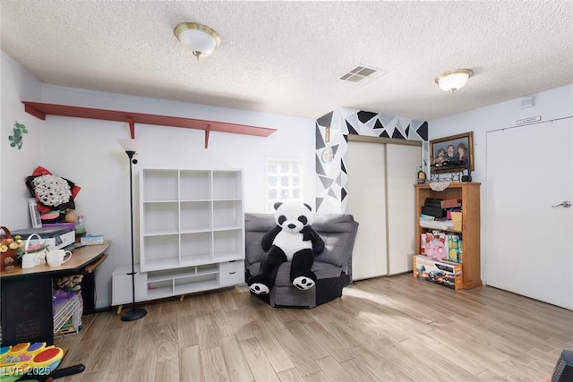 interior space featuring a textured ceiling, wood finished floors, and visible vents