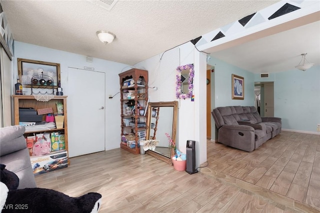 living area featuring visible vents, a textured ceiling, and wood finished floors