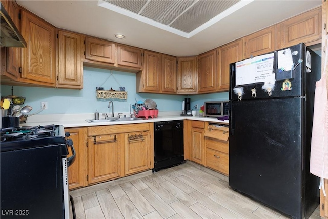 kitchen with light countertops, light wood-style flooring, a sink, under cabinet range hood, and black appliances