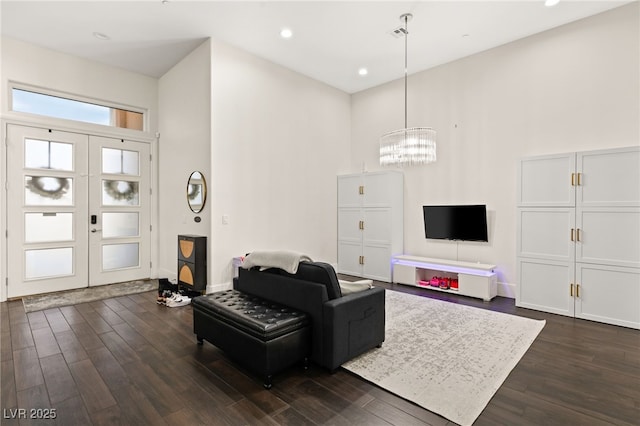 living room with dark wood-type flooring, a towering ceiling, and french doors