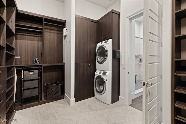 washroom featuring cabinets, light colored carpet, and stacked washer / dryer