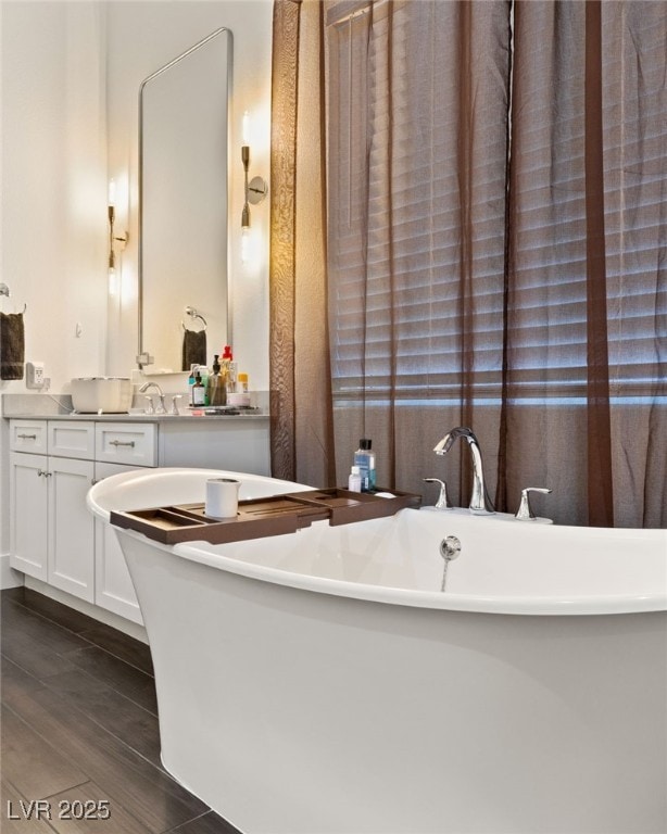 bathroom with wood-type flooring, a bathing tub, and vanity