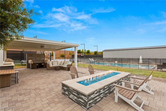 view of patio with a fenced in pool, an outdoor living space with a fire pit, and an outdoor kitchen