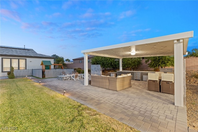 view of patio / terrace with exterior kitchen, ceiling fan, an outdoor hangout area, and a playground