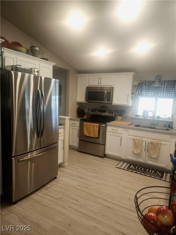 kitchen featuring white cabinetry, lofted ceiling, stainless steel appliances, and sink