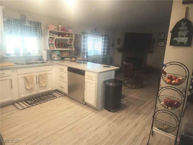 kitchen with white cabinetry, sink, stainless steel dishwasher, and kitchen peninsula