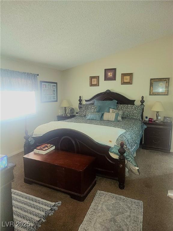 bedroom with vaulted ceiling, dark carpet, and a textured ceiling