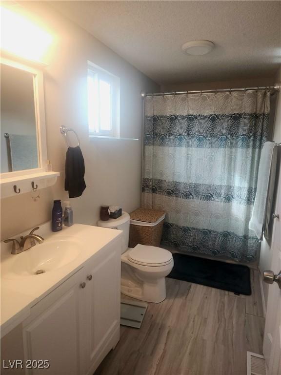 bathroom with hardwood / wood-style flooring, vanity, toilet, and walk in shower