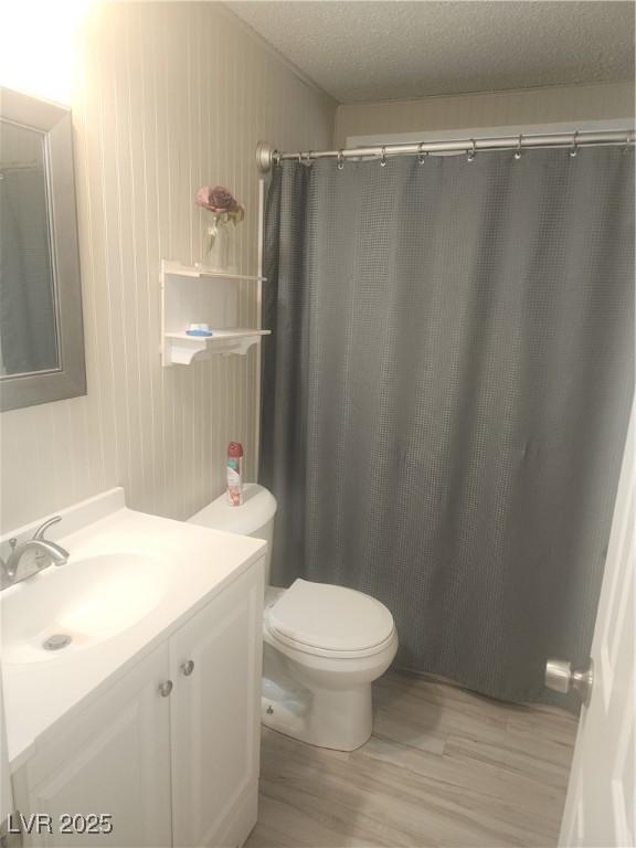 bathroom with vanity, wood-type flooring, a textured ceiling, toilet, and walk in shower