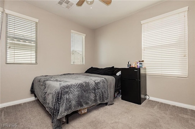 bedroom featuring freestanding refrigerator, visible vents, light carpet, and baseboards