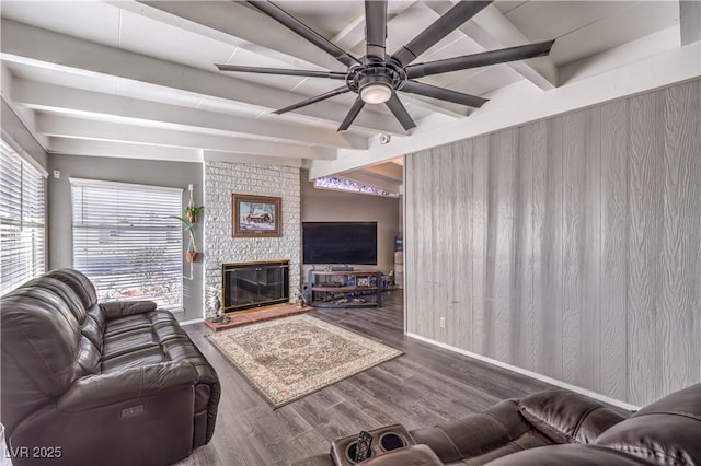 living room with dark wood-type flooring, ceiling fan, a fireplace, and lofted ceiling with beams