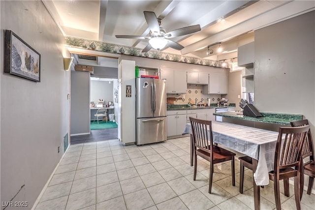 kitchen with light tile patterned floors, stainless steel fridge, ceiling fan, beam ceiling, and backsplash