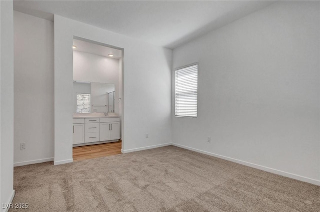 unfurnished bedroom featuring connected bathroom, sink, and light carpet