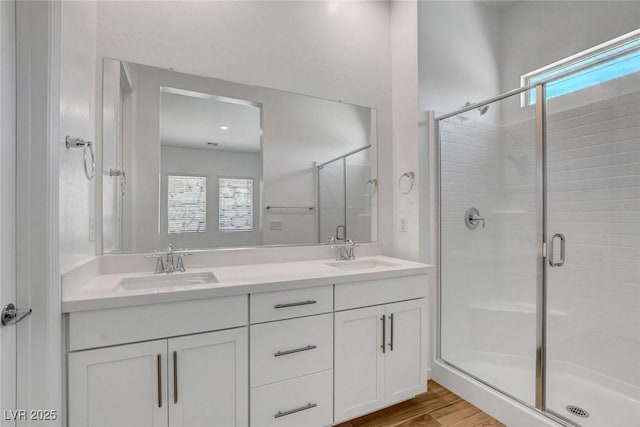 bathroom with hardwood / wood-style flooring, a healthy amount of sunlight, a shower with door, and vanity