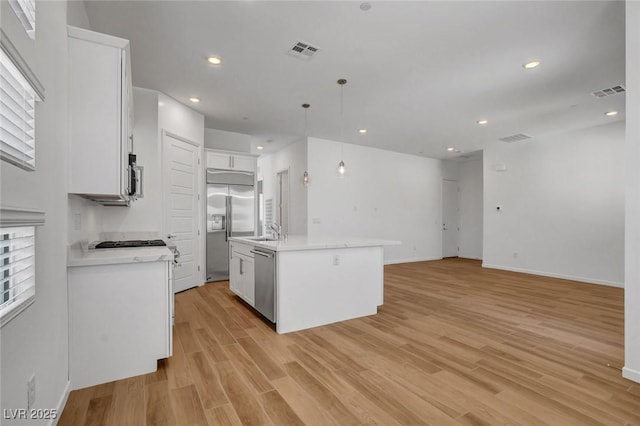 kitchen featuring pendant lighting, white cabinetry, a kitchen island with sink, light hardwood / wood-style floors, and stainless steel appliances