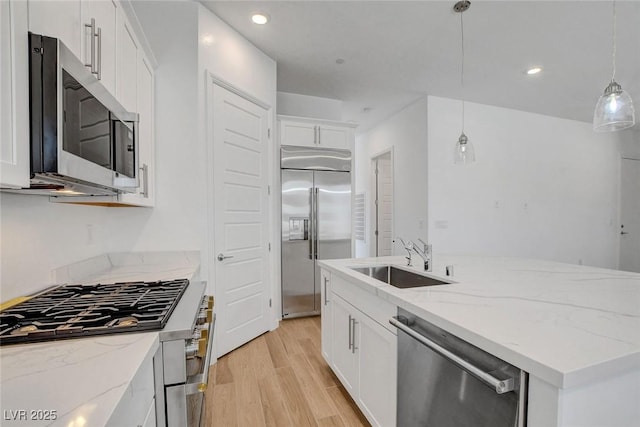 kitchen with sink, decorative light fixtures, light hardwood / wood-style flooring, stainless steel appliances, and white cabinets