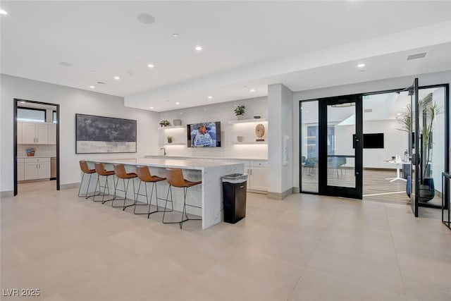 kitchen featuring french doors, white cabinetry, a breakfast bar area, and a spacious island