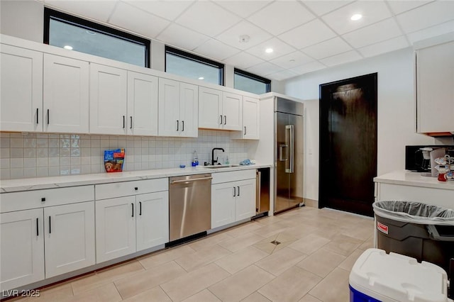 kitchen featuring light tile patterned flooring, appliances with stainless steel finishes, white cabinetry, sink, and decorative backsplash