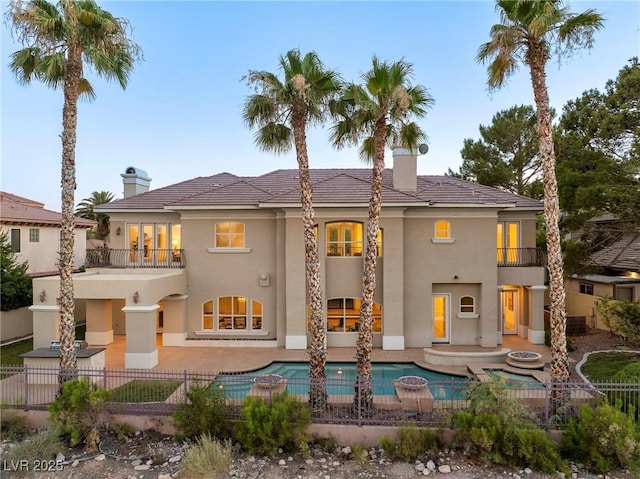 back of property featuring a fenced in pool, a patio, a chimney, stucco siding, and fence