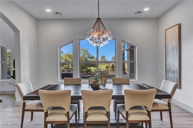 dining area with a chandelier, arched walkways, wood finished floors, and visible vents