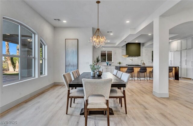 dining area with a notable chandelier and light hardwood / wood-style flooring