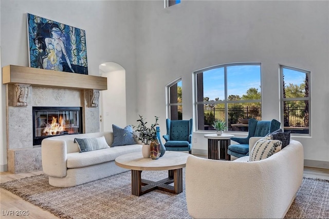 living area with a towering ceiling, wood finished floors, and a high end fireplace