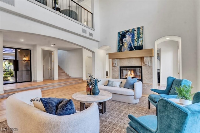 living area with arched walkways, a premium fireplace, wood finished floors, and visible vents