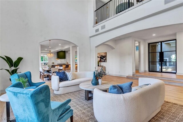 living room featuring an inviting chandelier, a towering ceiling, and wood-type flooring