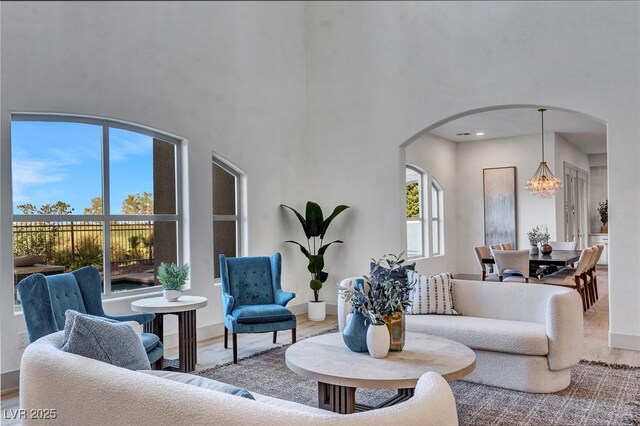 living room featuring an inviting chandelier, light hardwood / wood-style flooring, and a high ceiling