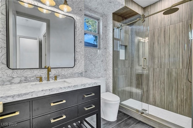 bathroom with vanity, a shower with shower door, and toilet