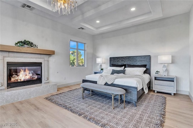 bedroom featuring a fireplace, light hardwood / wood-style flooring, and a chandelier