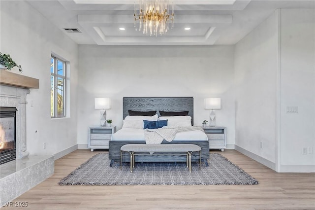 bedroom featuring hardwood / wood-style floors, a notable chandelier, and a multi sided fireplace