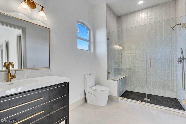 bathroom featuring vanity, a shower stall, toilet, and baseboards